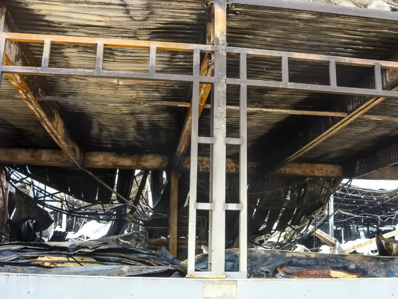 Charred and collapsed metal structure inside a burnt building.