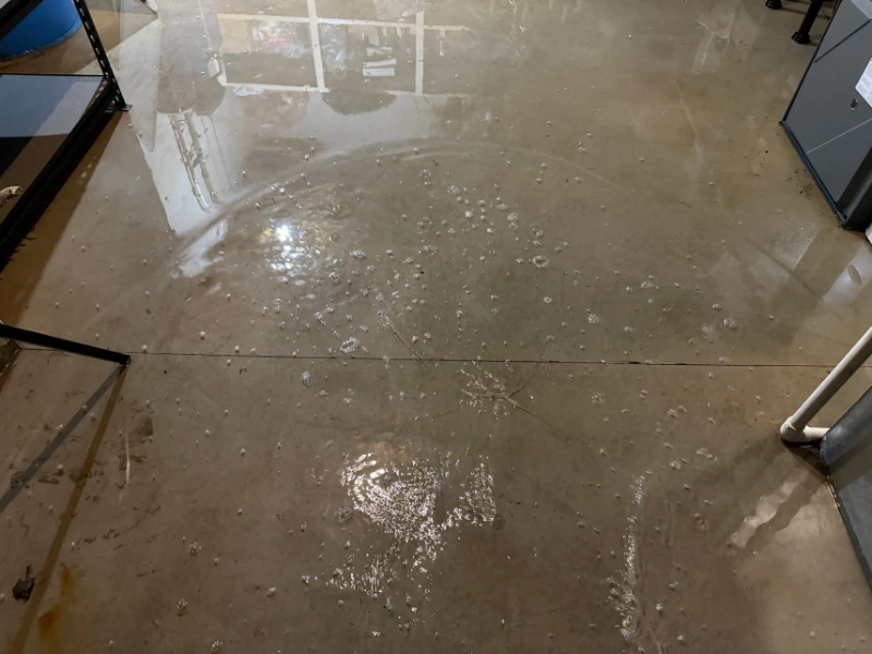 Concrete floor with scattered water droplets and reflections of nearby objects.